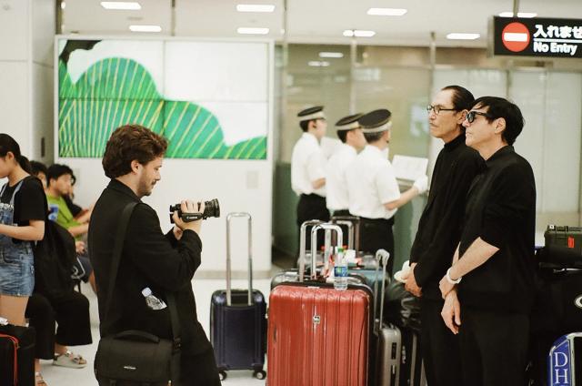 Ron Mael taking a picture of a person with a camera