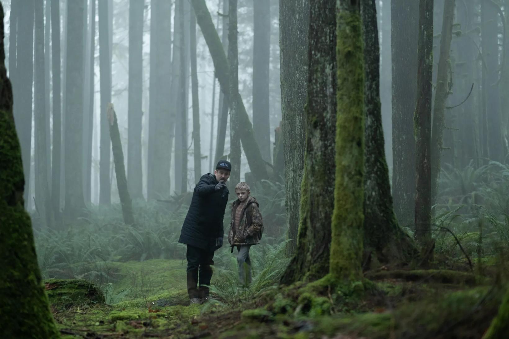 a man and woman standing in a forest