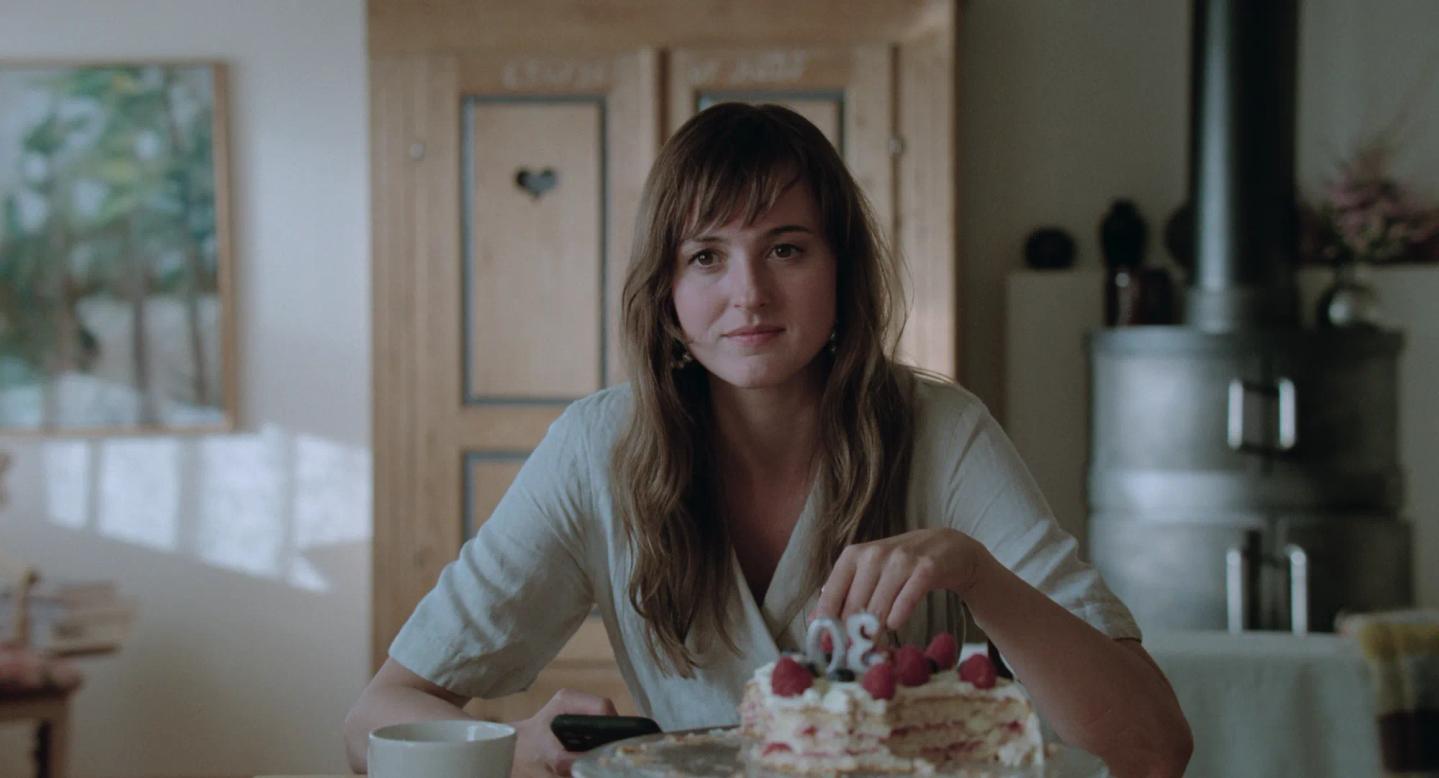 a woman sitting at a table with a cake