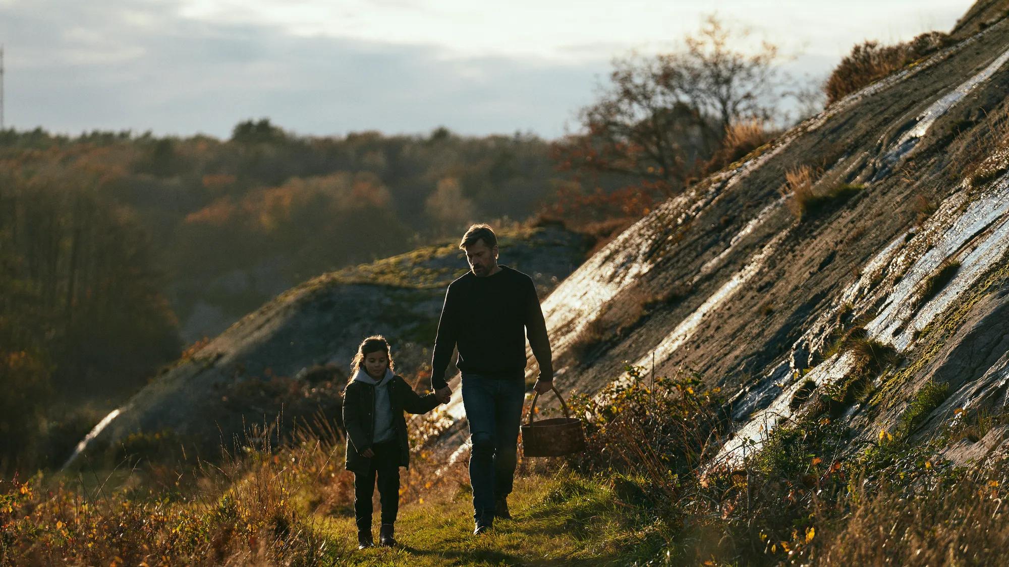 a man and a woman walking on a trail in a grassy area