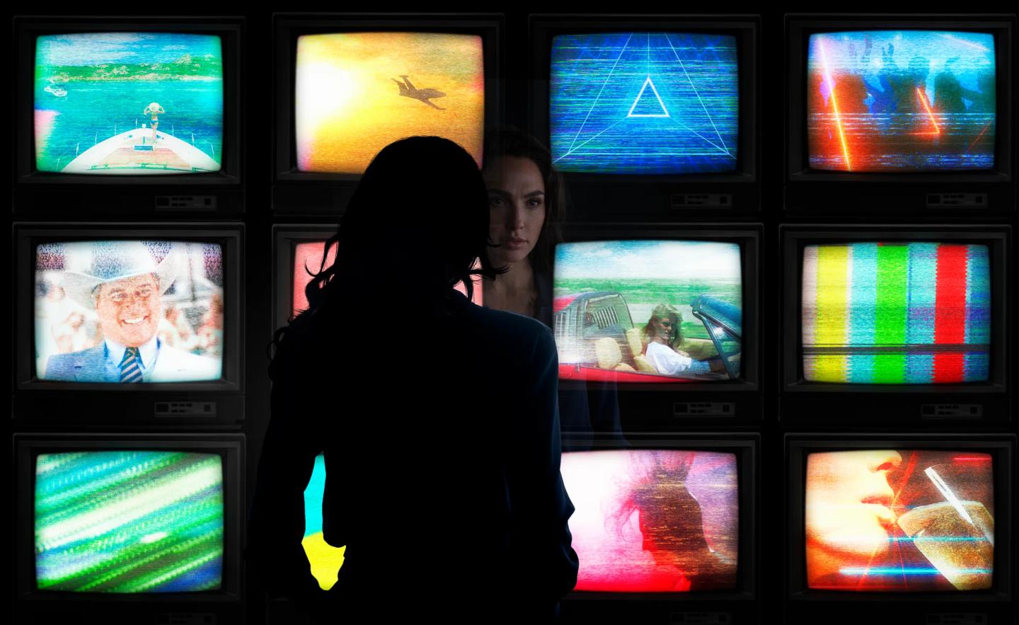 Gal Gadot standing in front of a wall of pictures