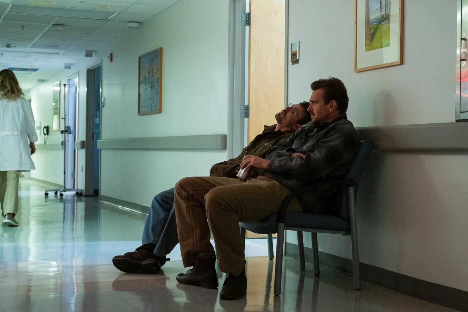 a man sitting in a chair with another man sitting on a bench