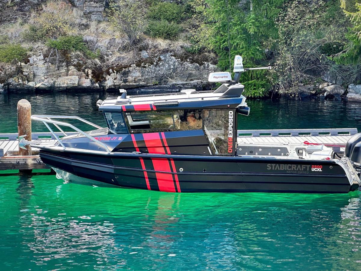 Our black cabin boat with red stripes, moored over clear emerald water
