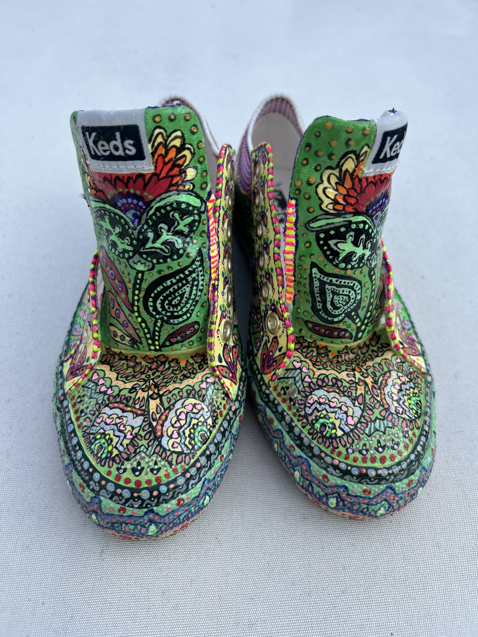 Front view of hand-painted Keds with intricate green patterns