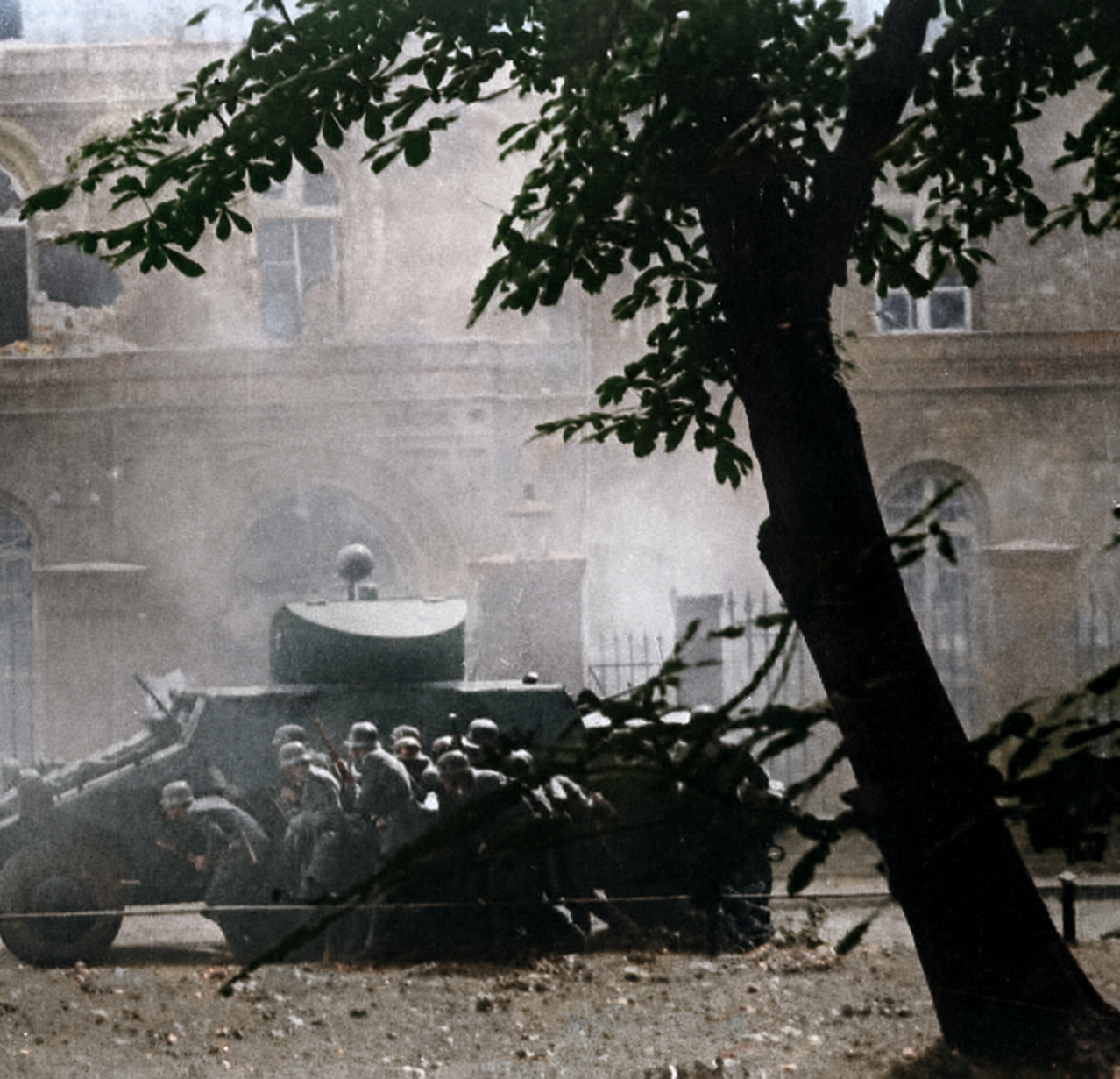 Troops in position around a large municipal building during an assault, smoke visible at street level.