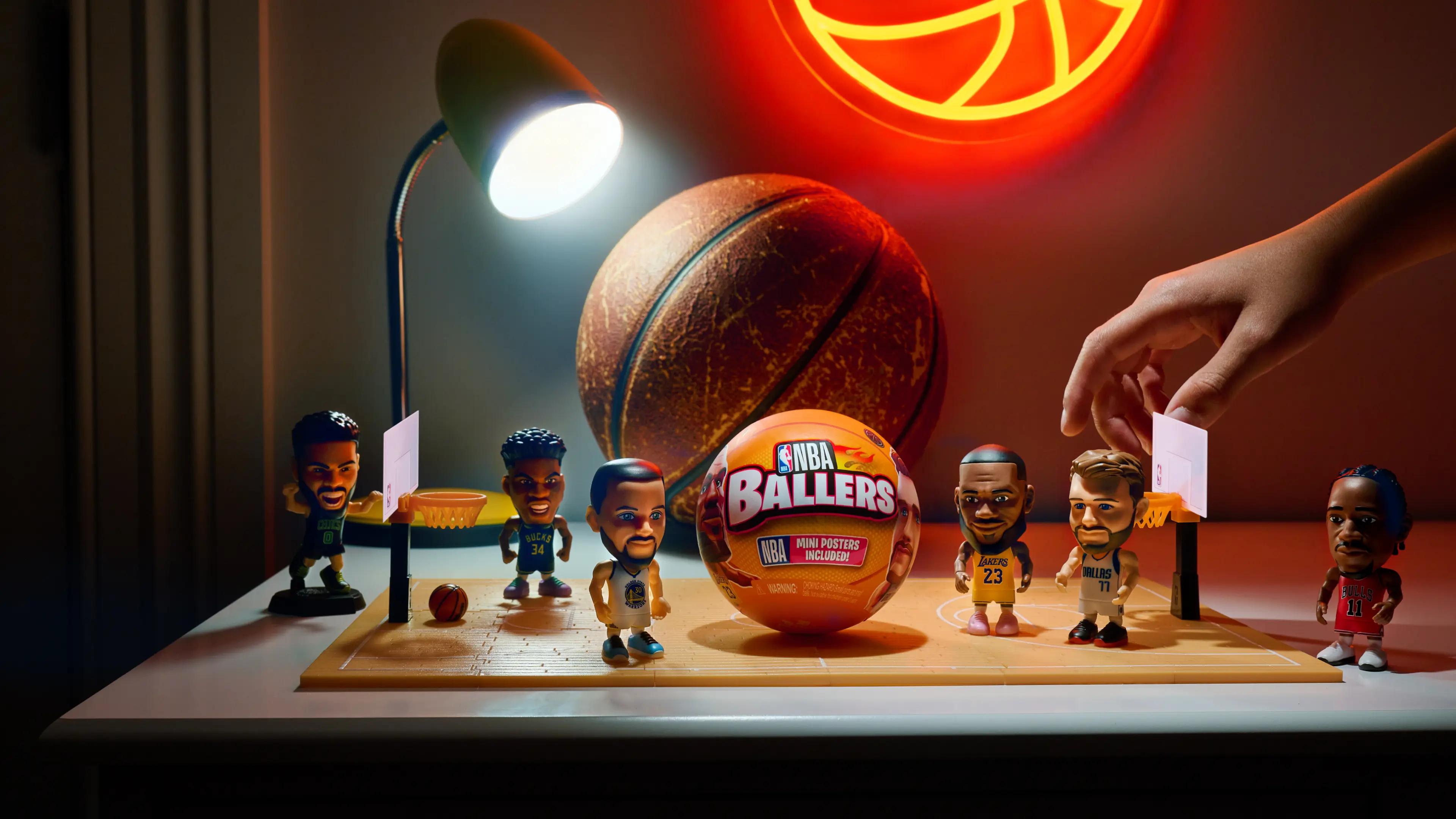 5 Surprise | NBA Ballers, hand reaching for collectible NBA Players on desk