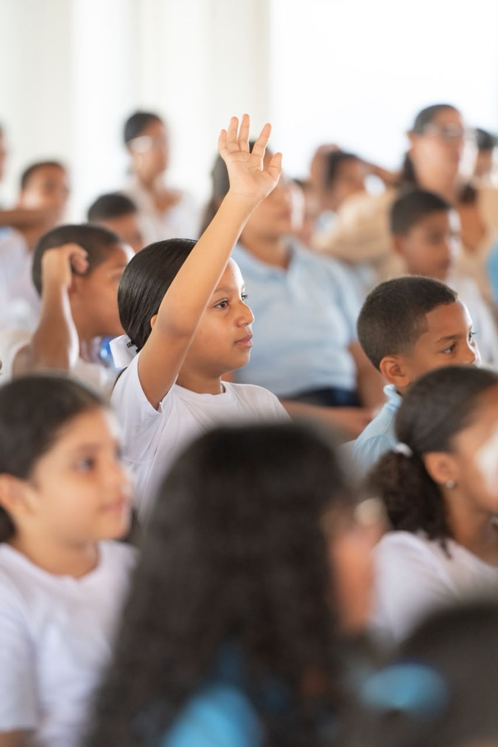 Una niña levanta la mano entre sus compañeros.
