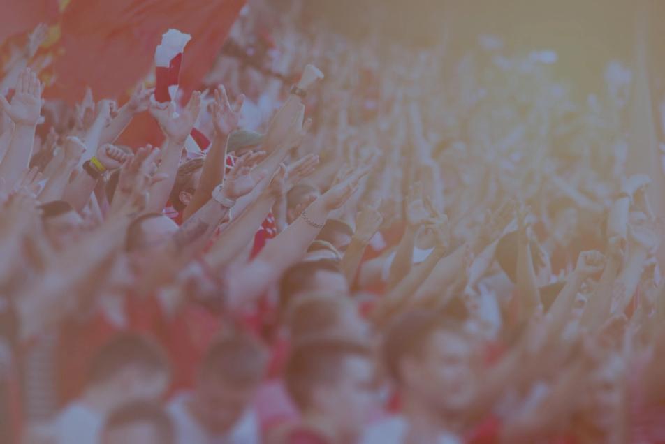 Fans watching a football match with their arms raised