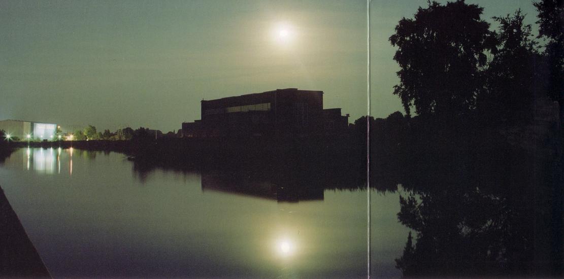 High contrast photo of lake reflecting the sun over a building. 