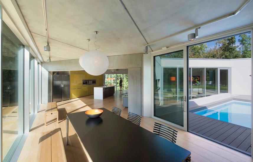 Dining area with glass windows and door open towards pool area 