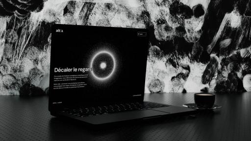 The Alt-a website open on a laptop, its headline “Décaler le regard” beside a glowing ring of light