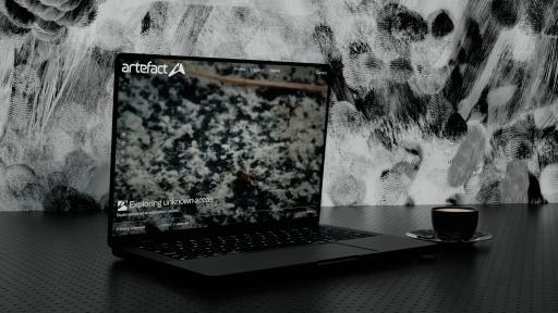 The Artefact website open on a laptop, a close-up of textured stone under the line “Exploring unknown areas”