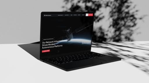 The BotBlox Systems website on a laptop in dappled tree shade: a satellite above Earth and a headline on autonomous platforms