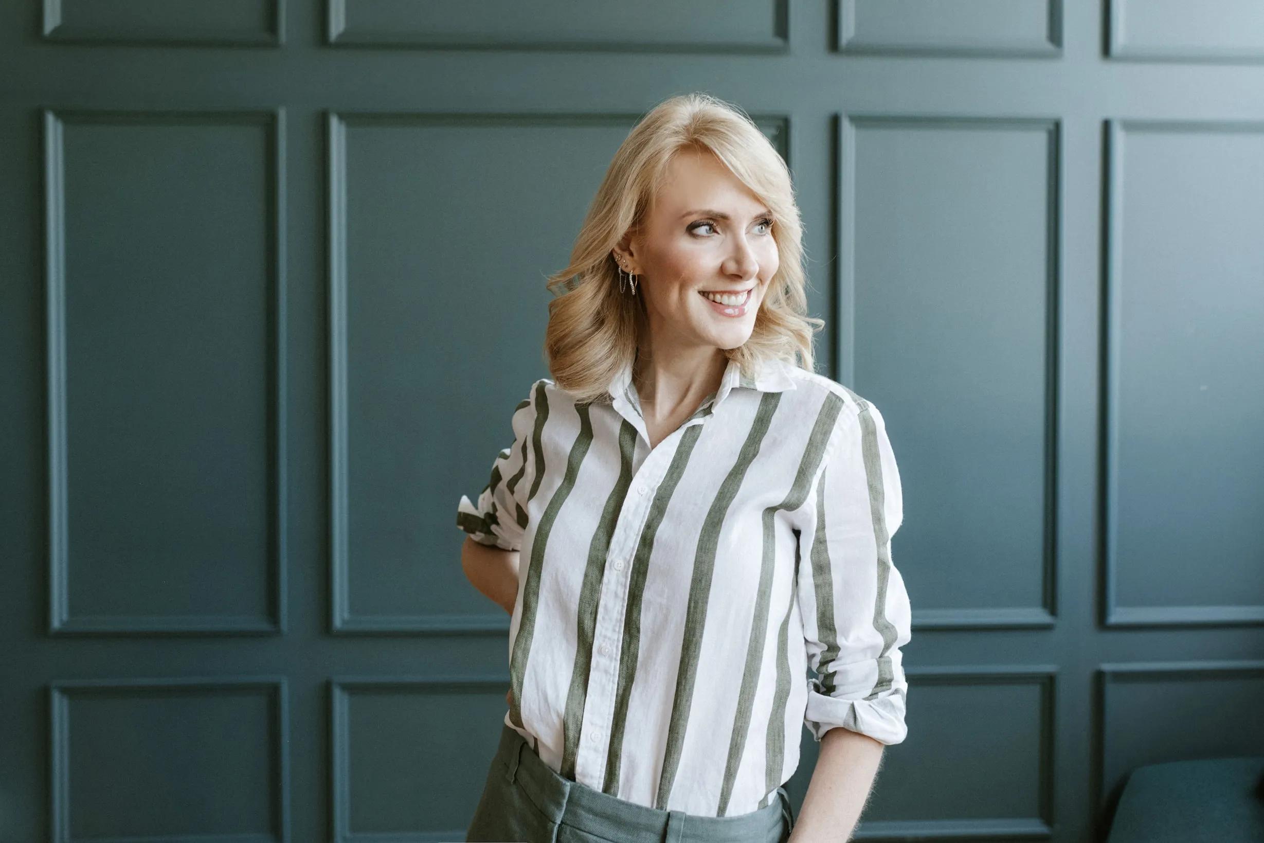 Sharon wearing a smile against a teal wall