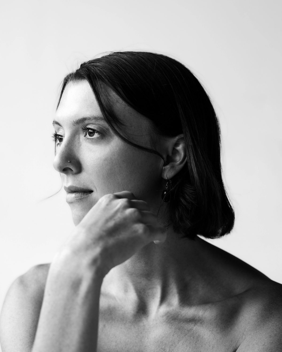 Black and white portrait of Isabelle, hand at her chin, looking away
