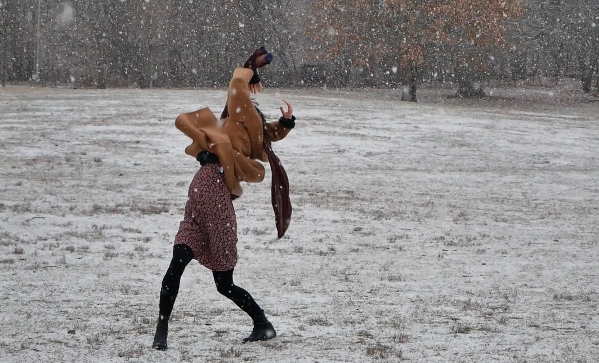 Isabelle dancing in a snowy field, a jacket swinging from her arm