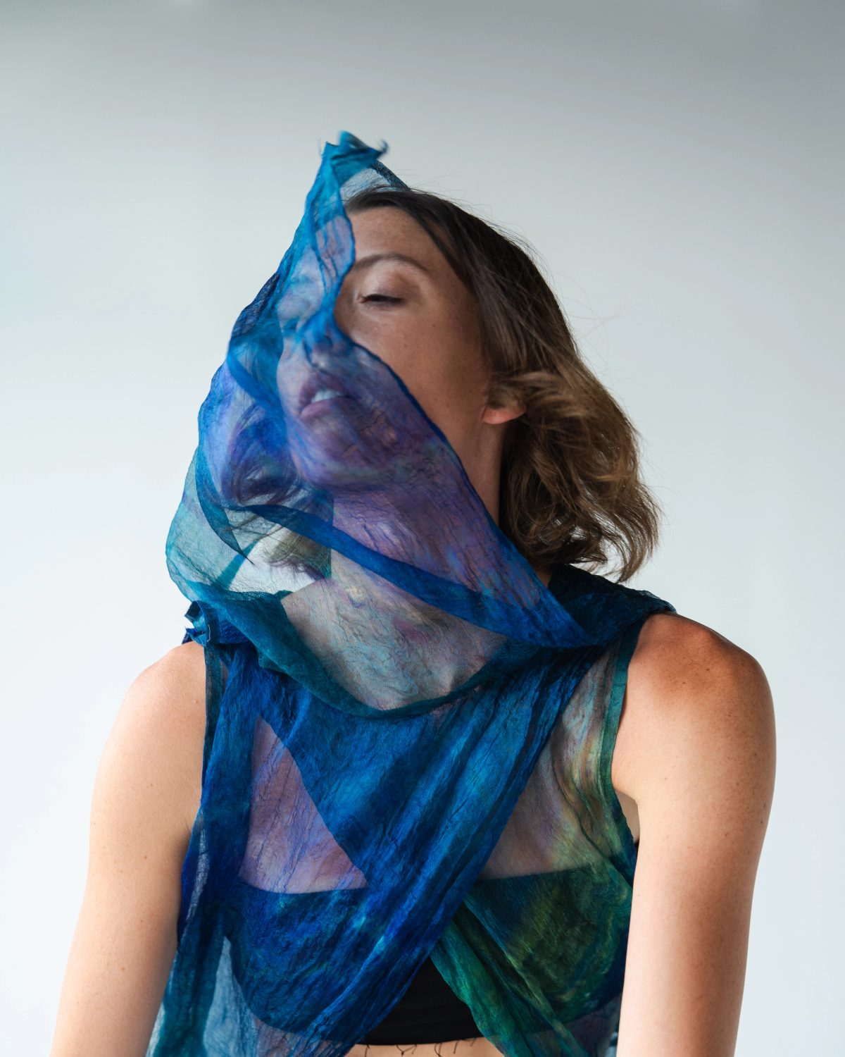 Isabelle with her face wrapped in sheer blue fabric