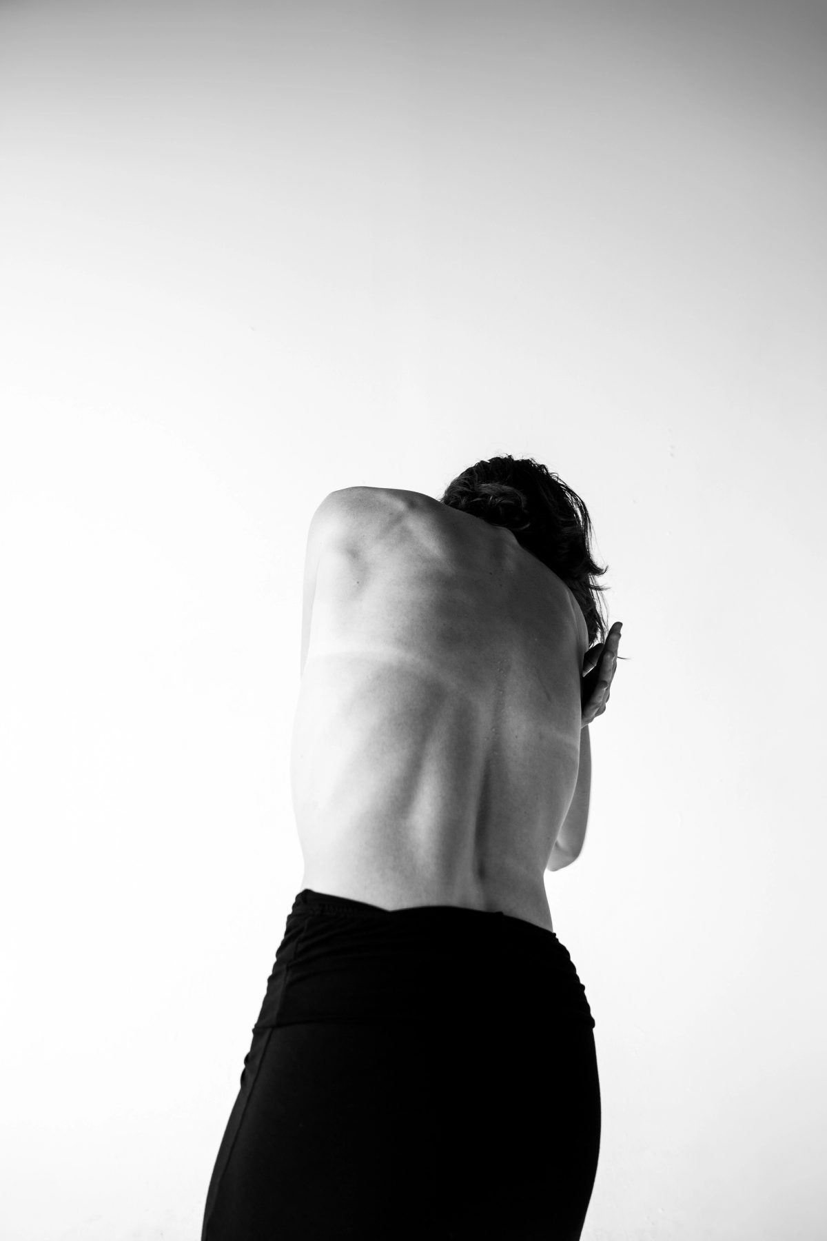 Black and white photo of Isabelle’s bare back, curled forward