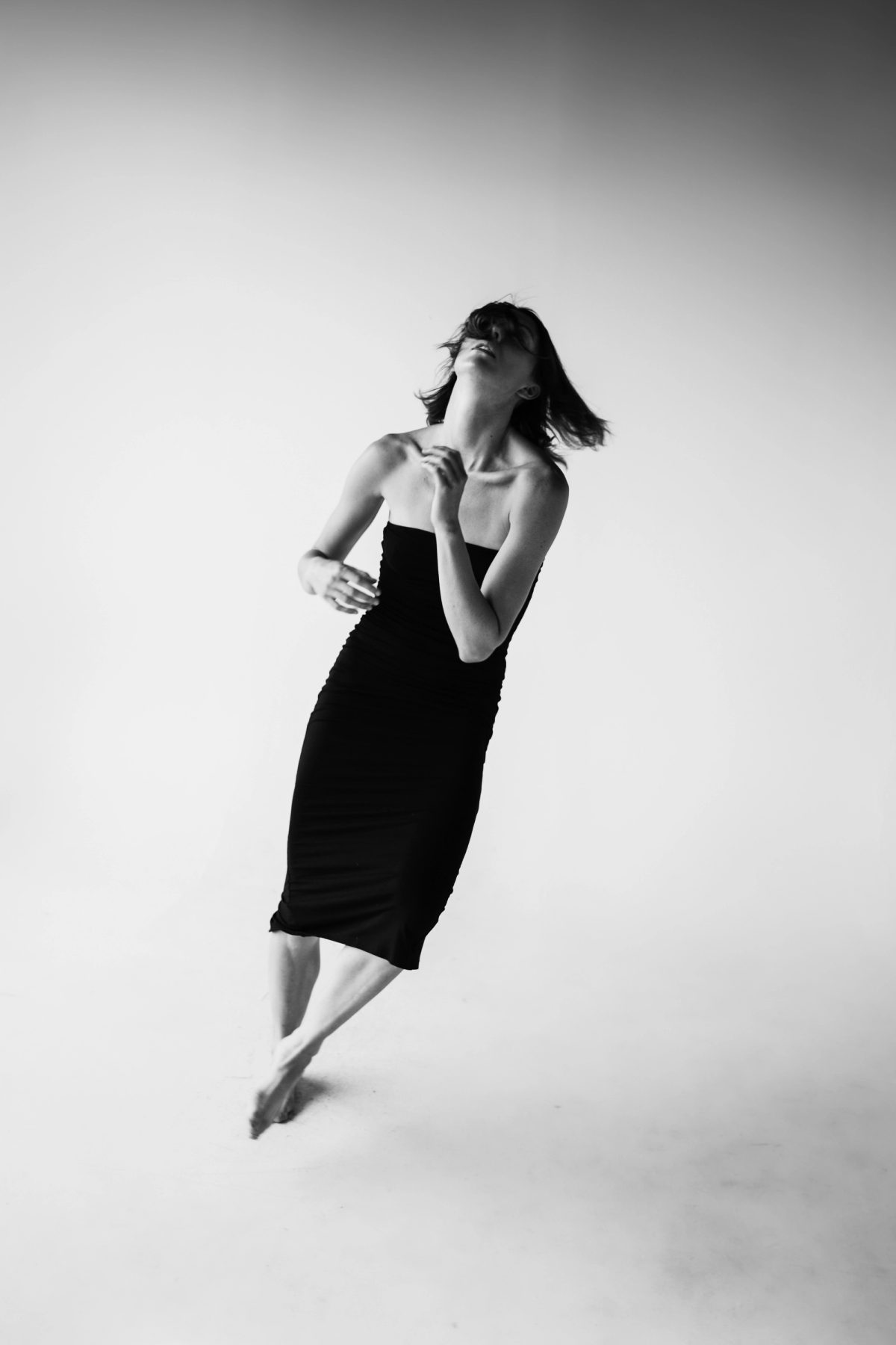 Black and white photo of Isabelle in a black dress, leaning back mid-movement