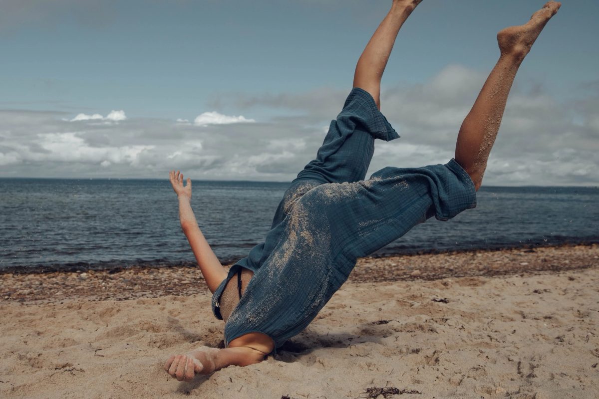 Isabelle falling sideways on a beach, legs in the air