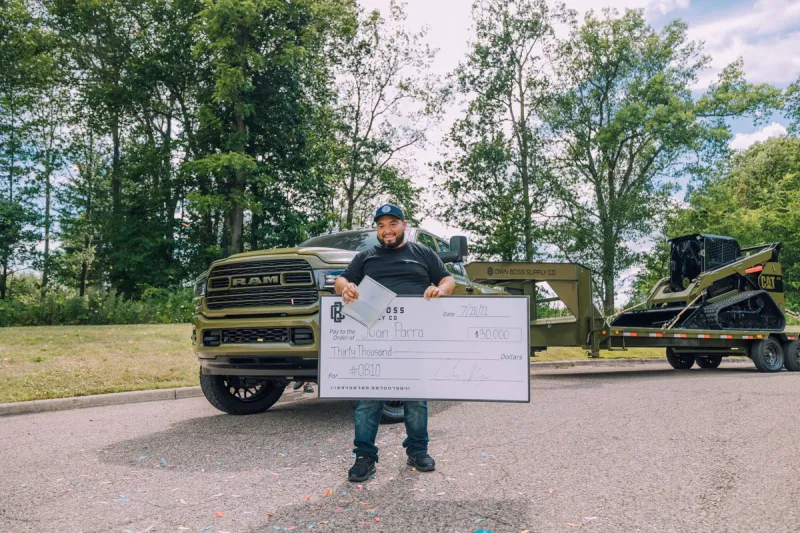 Juan holding his check, in front of OB10
