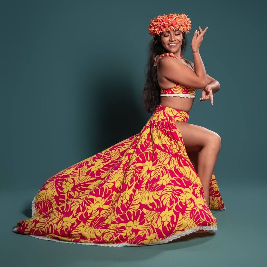 Isa Pérez performing ʻOri Tahiti in a red and yellow Tahitian costume and flower crown