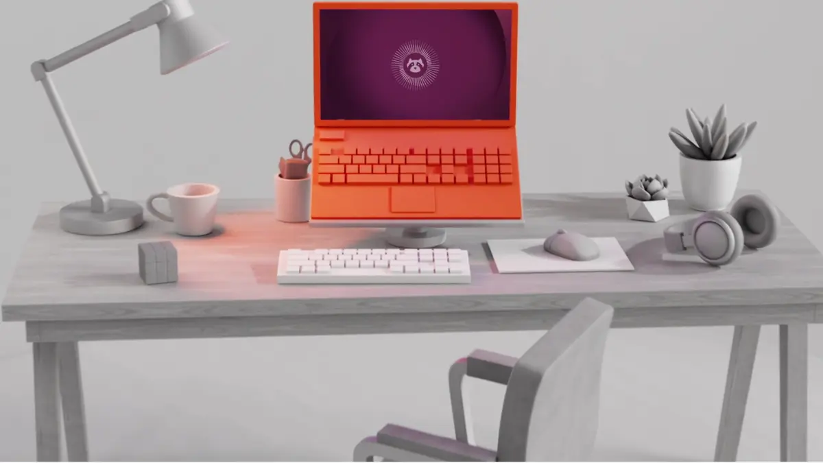 An orange Ubuntu laptop on a desk showing the Ubuntu desktop, surrounded by a keyboard, mouse, headphones and plants