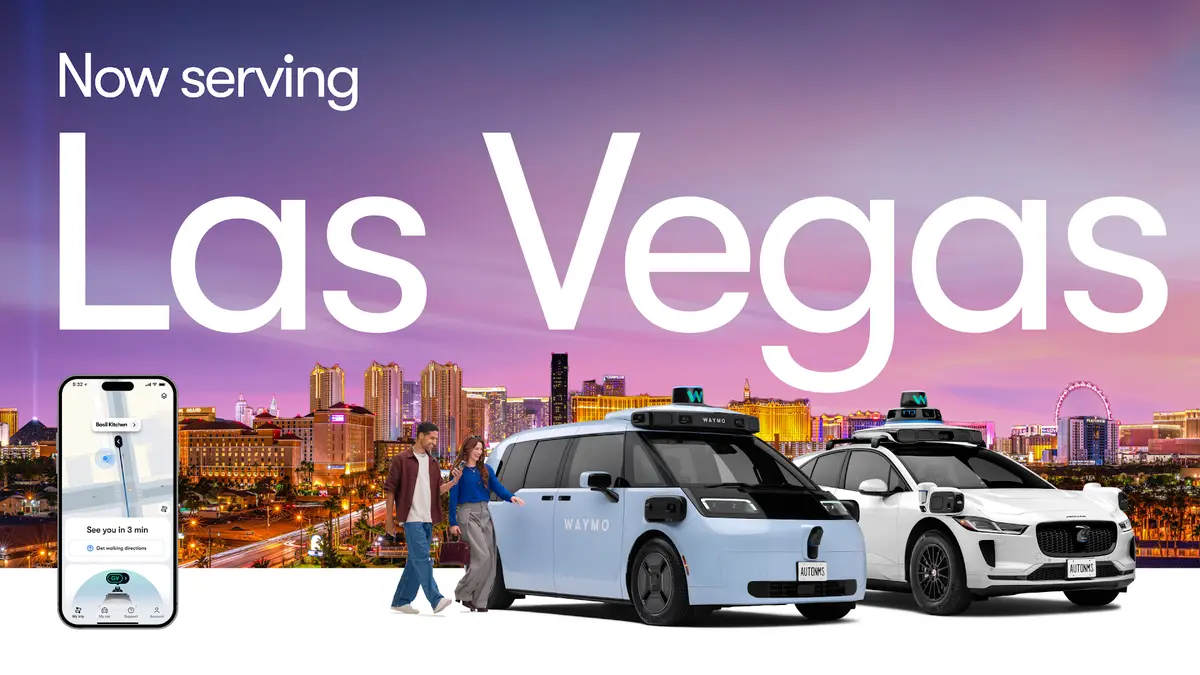 Two Waymo robotaxis on a neon-lit Las Vegas street with the city skyline behind them, a phone showing the Waymo app in the foreground and the words 'Now serving Las Vegas' across the image.