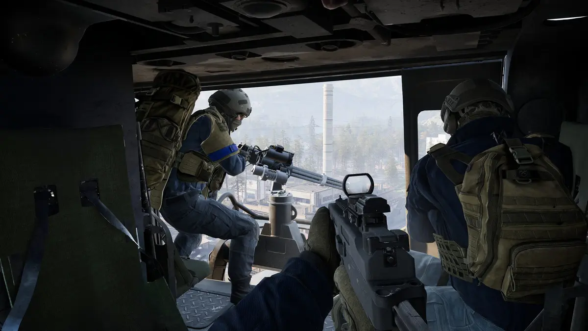 WARDOGS players in tactical gear firing from the open door of a transport helicopter above an industrial valley