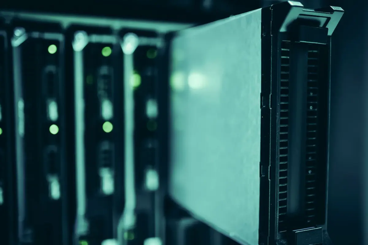 Close-up of server racks in a dimly lit data centre aisle, with drive bays glowing green