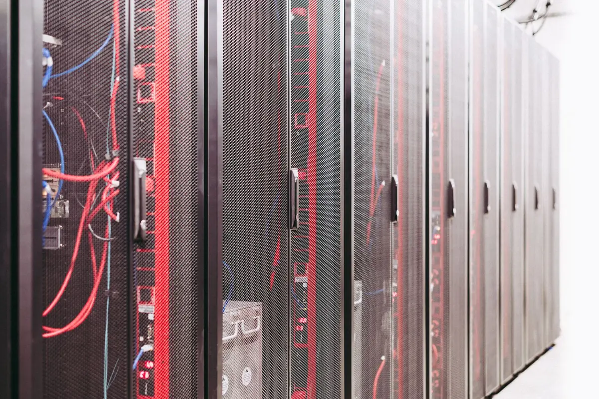 Rows of dark server racks lit by blue status lights in a data centre aisle