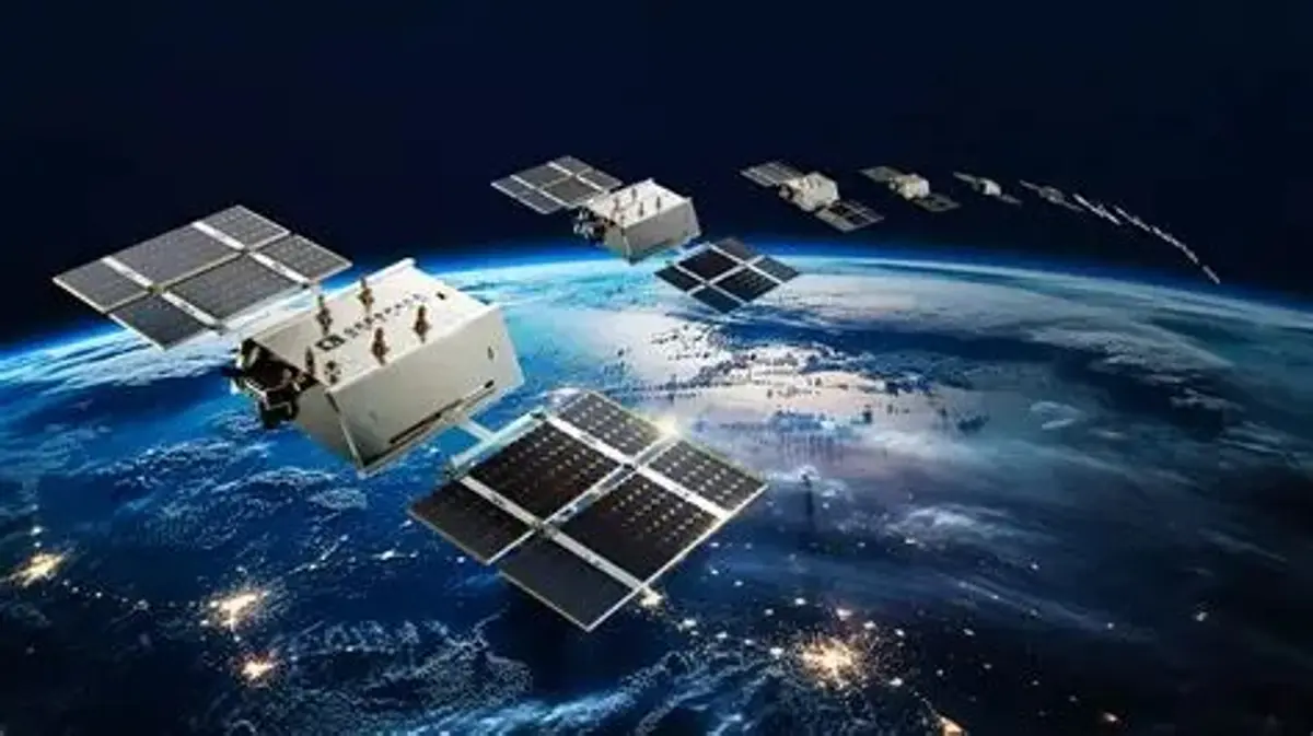 Illustration of low-Earth-orbit communications satellites with solar arrays above Earth at night.
