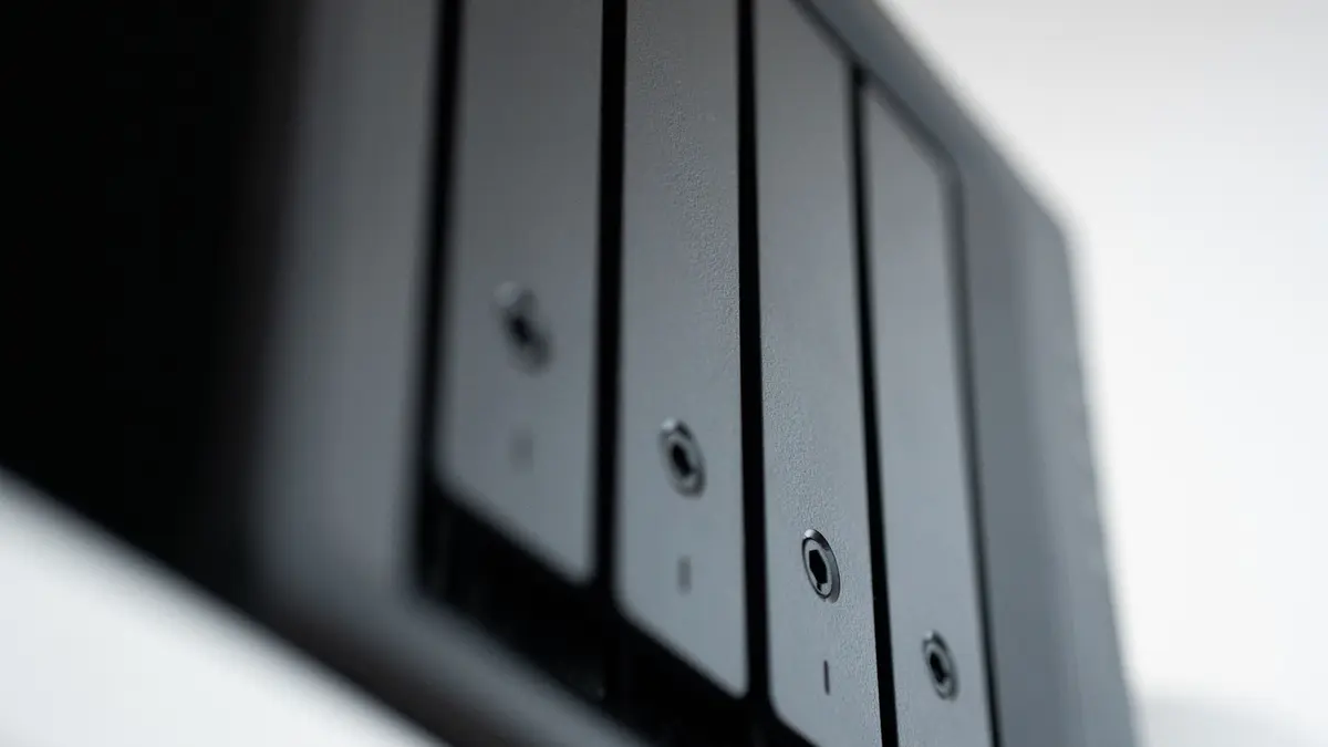 Close-up of the black drive bays of a desktop network storage enclosure, photographed at an angle against a pale background.