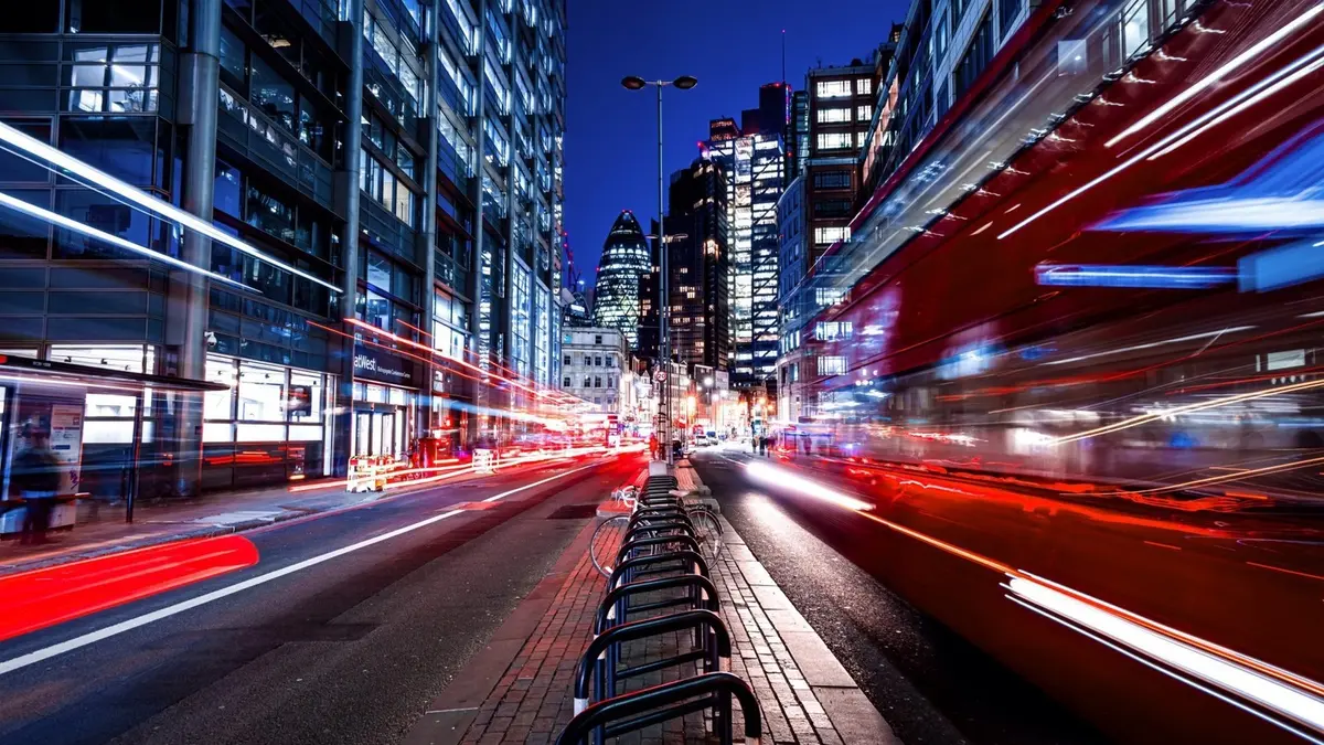 A night-time city street lit by neon shopfronts and blurred traffic trails, used by Lenovo as the lead image for its account of the DKSH smart-parking deployment