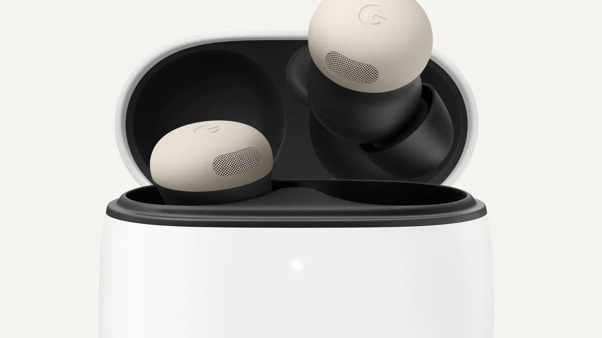 Two Google Pixel Buds earbuds resting inside an open white charging case on a pale background.