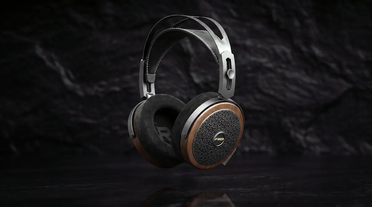 FiiO's FT15 open-back planar headphones photographed against dark stone, showing the walnut earcup with its perforated grille and the FiiO badge, a black leather headband and a silver metal yoke