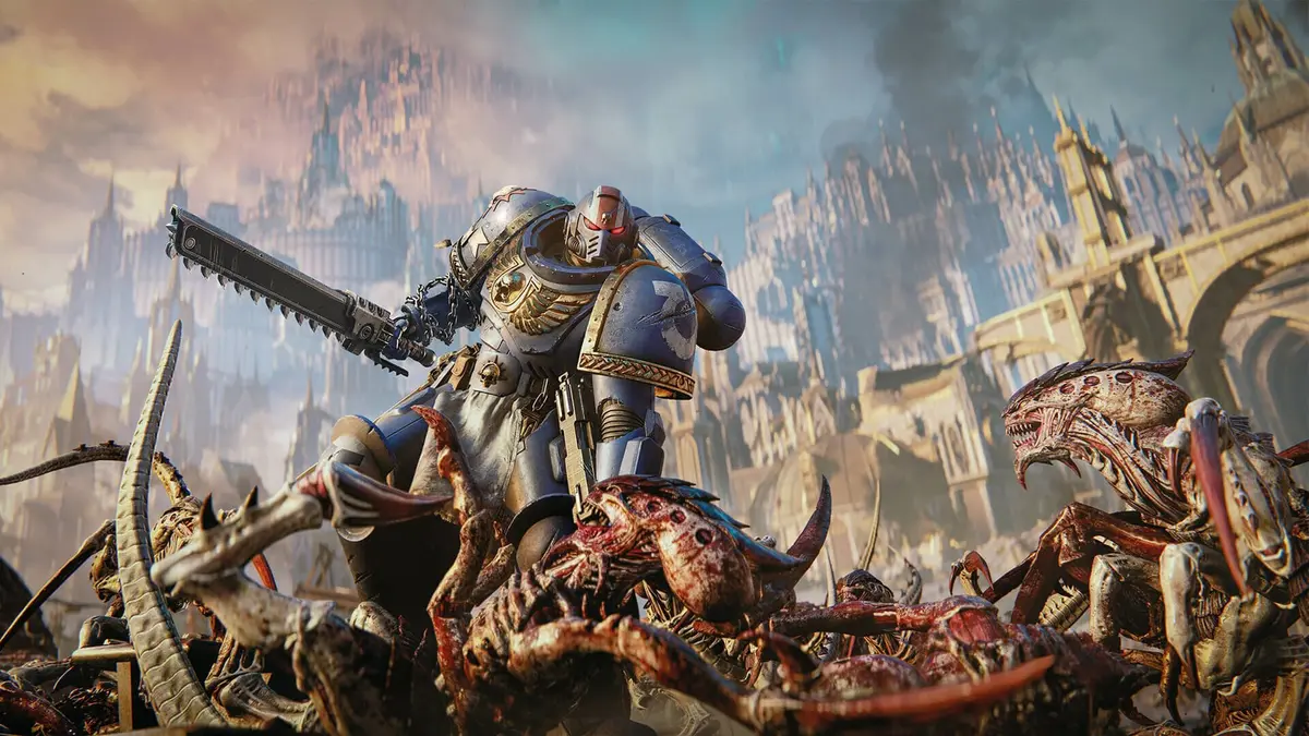 An Ultramarine in blue power armour swings a chainsword over dead Tyranids in front of an Imperial hive city in Warhammer 40,000: Space Marine 2