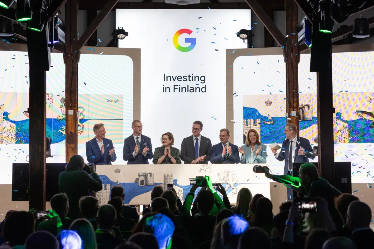 Executives and officials applauding on a stage beneath a screen reading “Investing in Finland” at Google’s announcement event in Helsinki