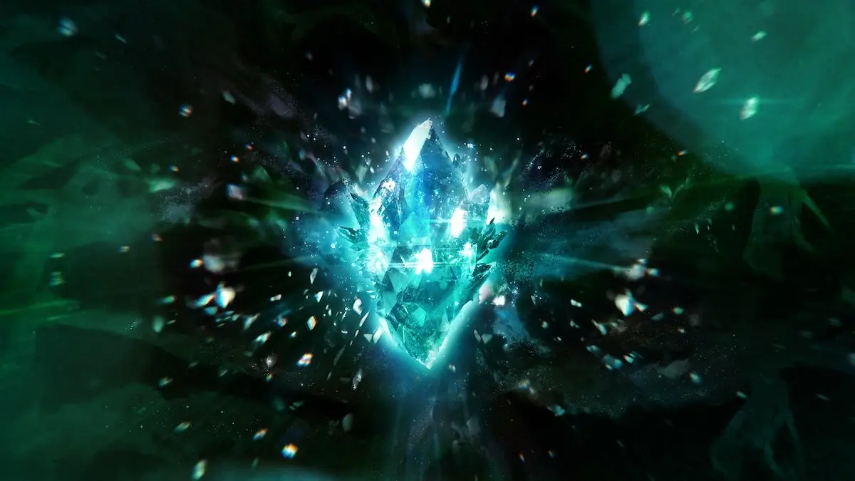 The official Final Fantasy 40th anniversary artwork: a glowing blue-white crystal shattering into shards and sparks against a dark teal-green background