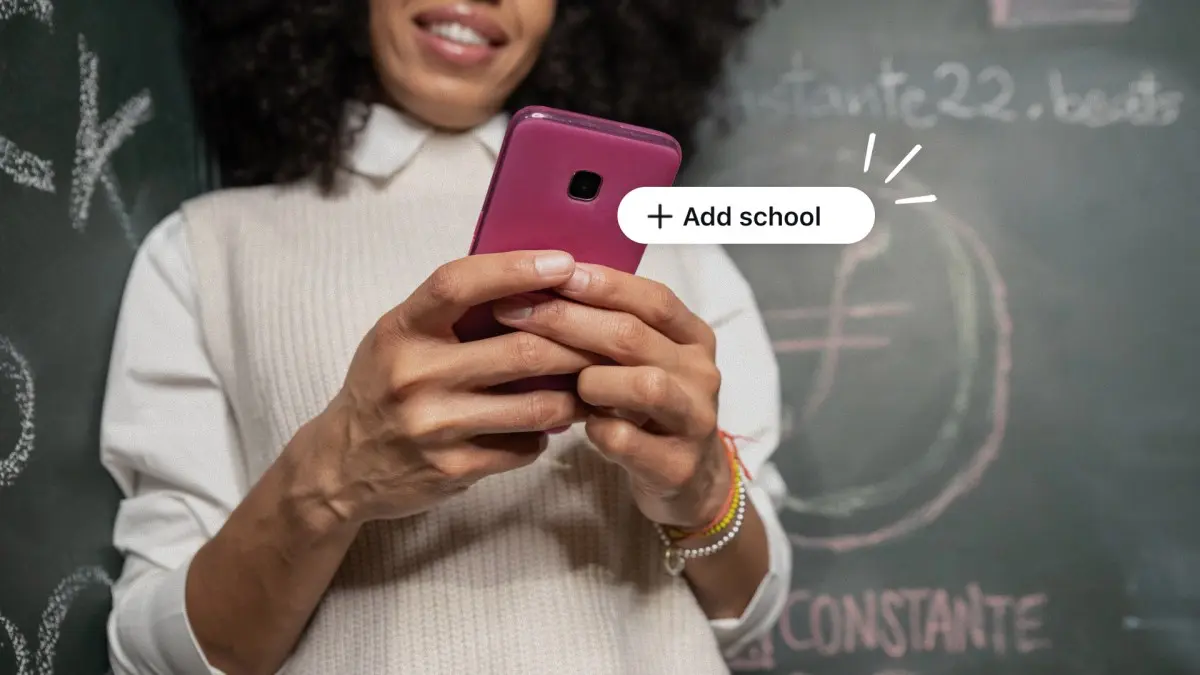 A photograph of a smiling young person in a white collared top holding a magenta smartphone in both hands in front of a dark green chalkboard covered in chalk writing, with a white rounded “+ Add school” button graphic floating beside the phone