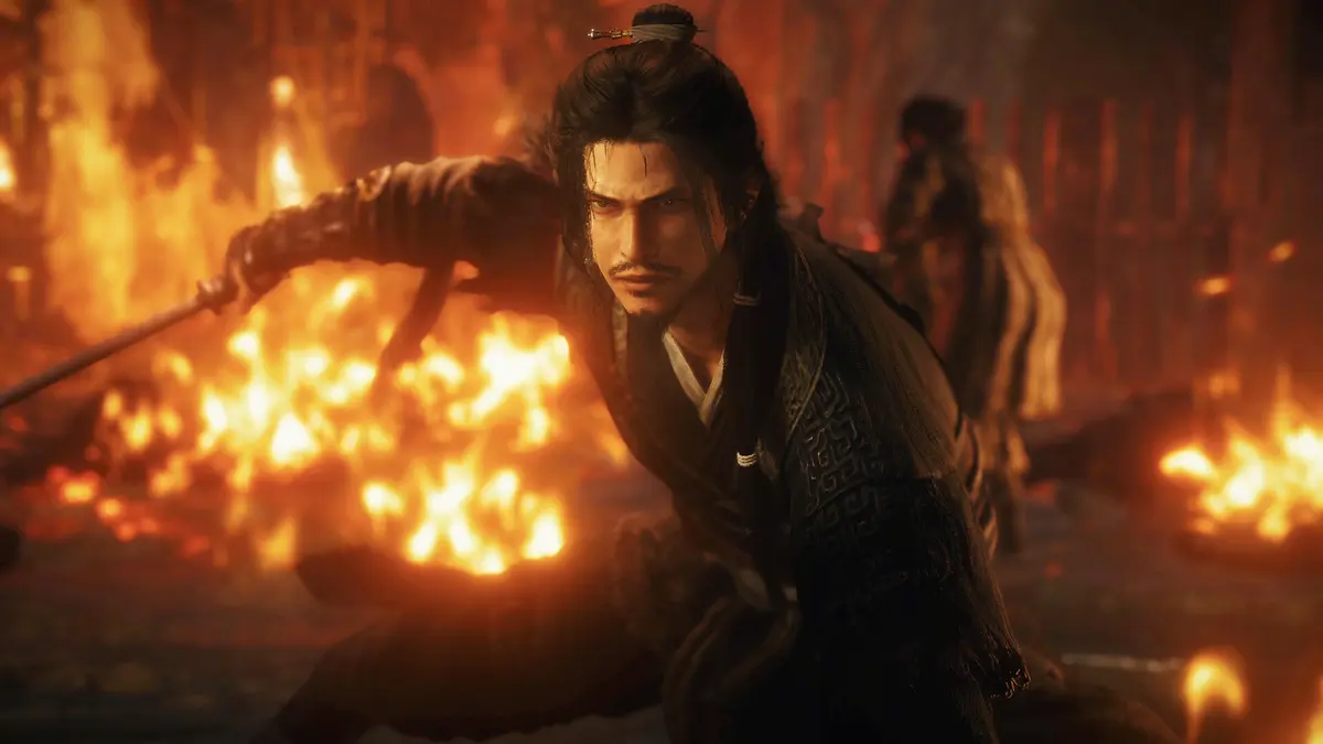 A warrior in dark armour lunges with a polearm through a burning battlefield, embers streaming past his face while another figure fights behind him.