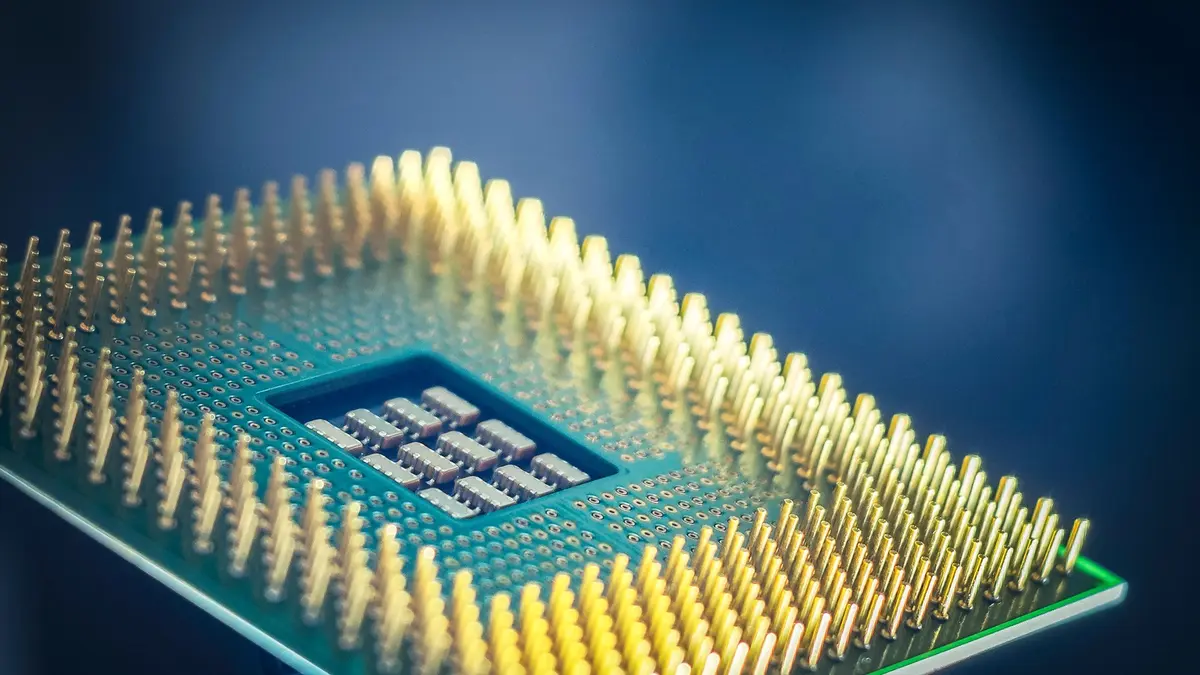 The gold contact pins of a computer processor resting on a blue background