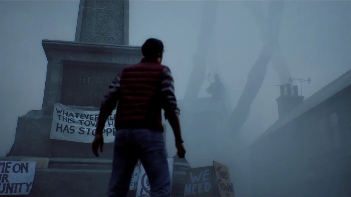 Simon Ordell, seen from behind in a striped top, standing in a foggy town square in front of a stone monument reading Heart of St Amelia, with protest placards resting on the steps and a distant figure looming in the mist.