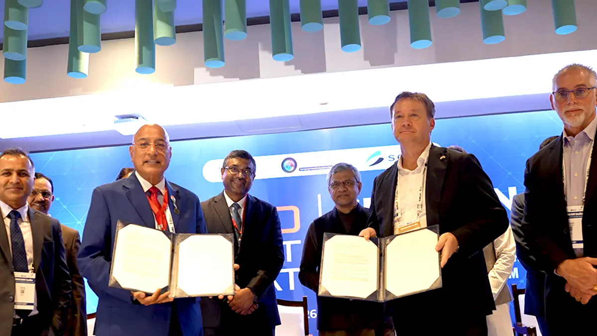 Nexperia and Tata Electronics executives on stage holding signed partnership documents at the announcement ceremony