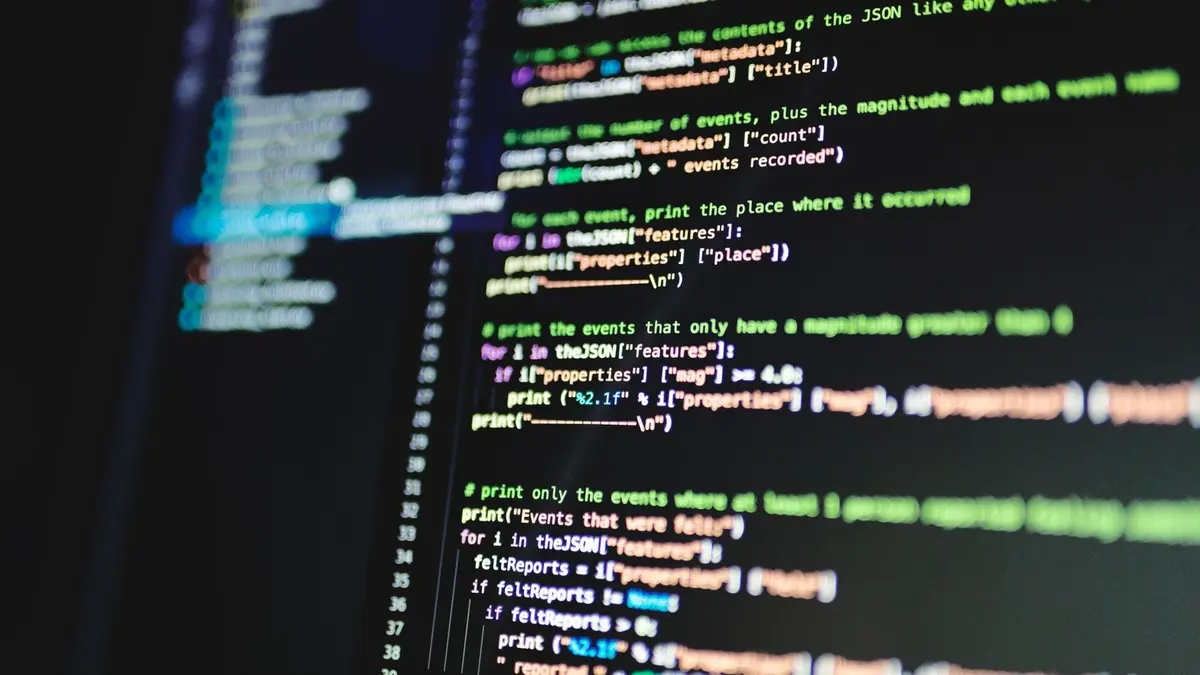Close-up of colour-coded lines of programming code displayed on a computer monitor in a darkened room