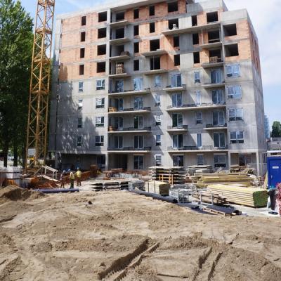 Construction site with a multi-story building, partially complete with concrete and brick, and a tall yellow crane.