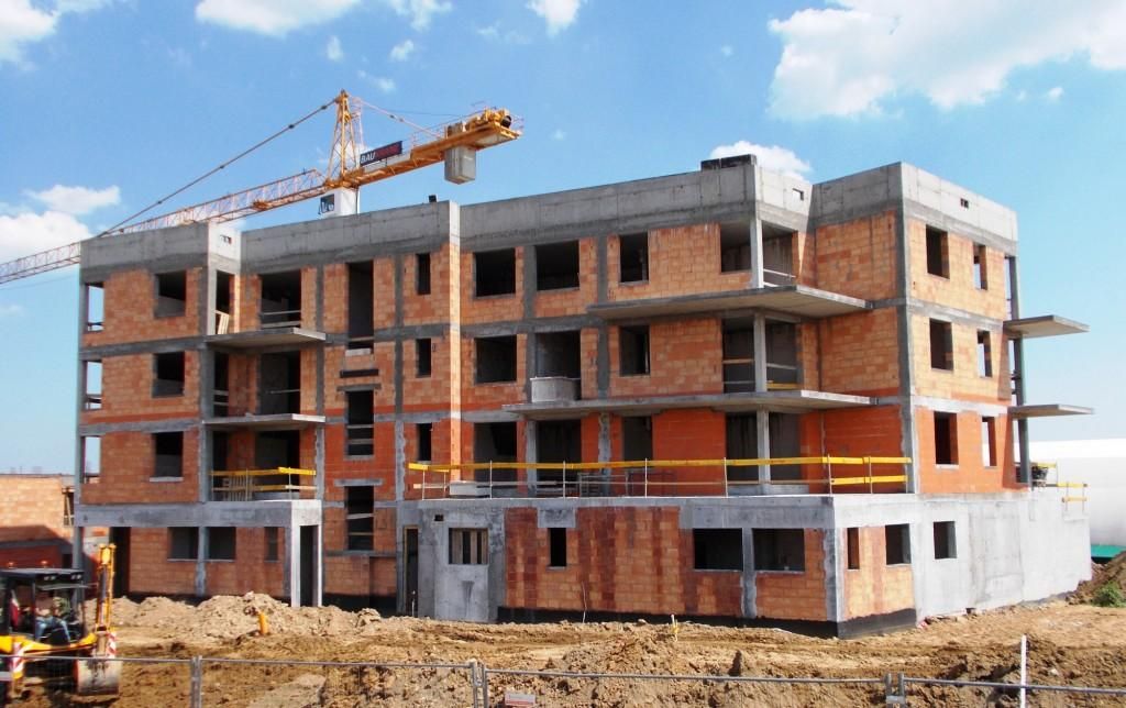 Budowa budynku wielopiętrowego przy użyciu dźwigu i koparki.