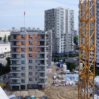 Construction site with a yellow tower crane, a building under construction, and finished apartment blocks.