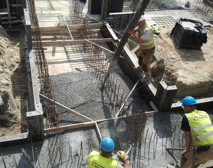 Robotnicy budowlani wylewający beton do fundamentu.