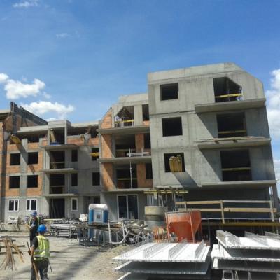 Construction site with multi-story buildings, concrete frames, brickwork, workers, and materials.